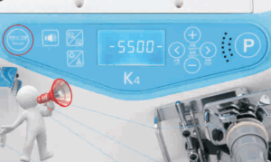 Dixie Tailoring Supply A close-up of the Jack K4 UT Automatic Coverstitch Sewing Machine's blue and white control panel displaying “-5500” with various buttons, featuring a 3D person figure with a megaphone in the lower left corner. Tailoring Supplies