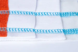 Dixie Tailoring Supply Close-up of white and orange fabric stitched with blue thread, displaying detailed overlock seams created by the Jack K5 UT01GB Automatic Cylinder Arm Coverstitch Industrial Sewing Machine. Tailoring Supplies