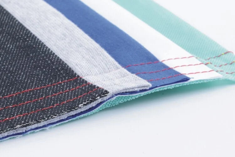 Dixie Tailoring Supply Close-up of four stacked fabric swatches in various colors and textures, each featuring visible red stitching along the edges, created using the JACK A2S Automatic Industrial Single Needle Sewing Machine. Tailoring Supplies