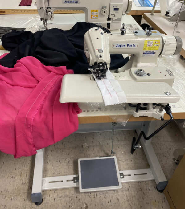 Dixie Tailoring Supply In a bustling tailoring store, the Japanfuji Blind Stitch Industrial Sewing Machine expertly stitches white fabric amidst an array of black and pink fabric pieces. Tailoring Supplies