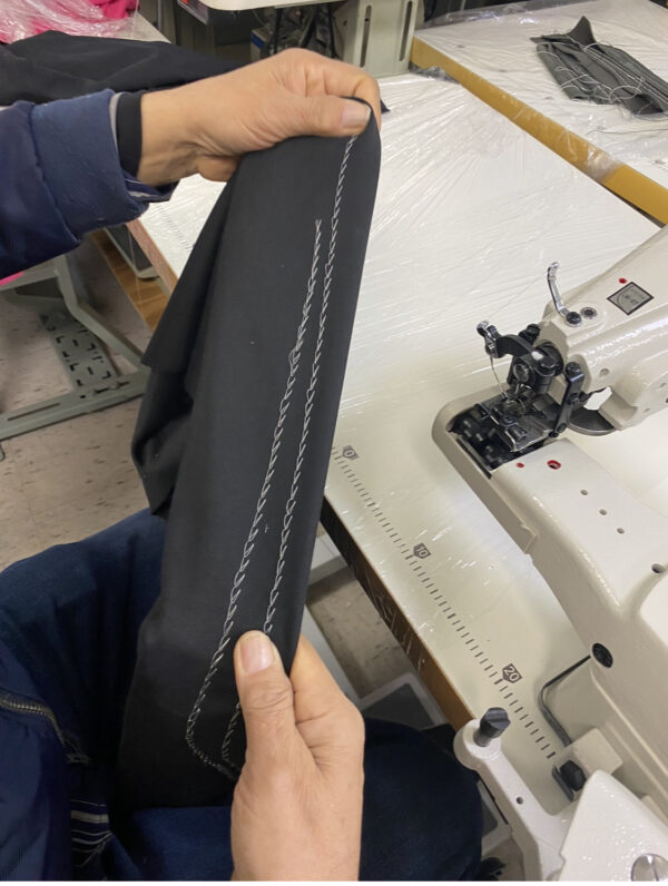 Dixie Tailoring Supply A person showcases a black fabric piece with white stitches, emphasizing the precision of Japanfuji Blind Stitch Industrial Sewing Machine products. Tailoring Supplies
