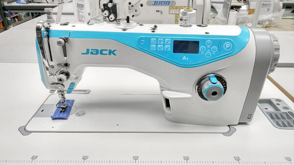 Dixie Tailoring Supply The JACK A4 Fully Automatic Industrial Sewing Machine, with blue and grey accents on a table, includes controls and a thread spool holder—perfect for tailoring stores seeking quality machines. Tailoring Supplies