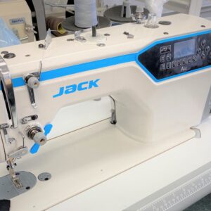 Dixie Tailoring Supply Close-up of a JACK A4E Computerised Lockstitch Sewing Machine with electronic control stitch length, in white and blue, sitting on a flat work surface in a lively tailoring store. Tailoring Supplies