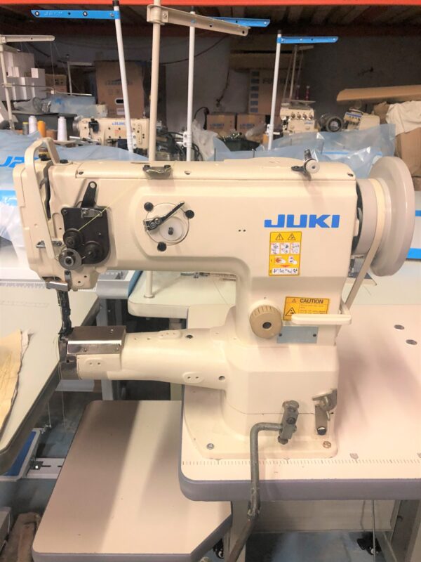 Dixie Tailoring Supply A JUKI LS 1341 USED industrial sewing machine is set up in a tailoring store workshop, surrounded by several other similar machines. Tailoring Supplies