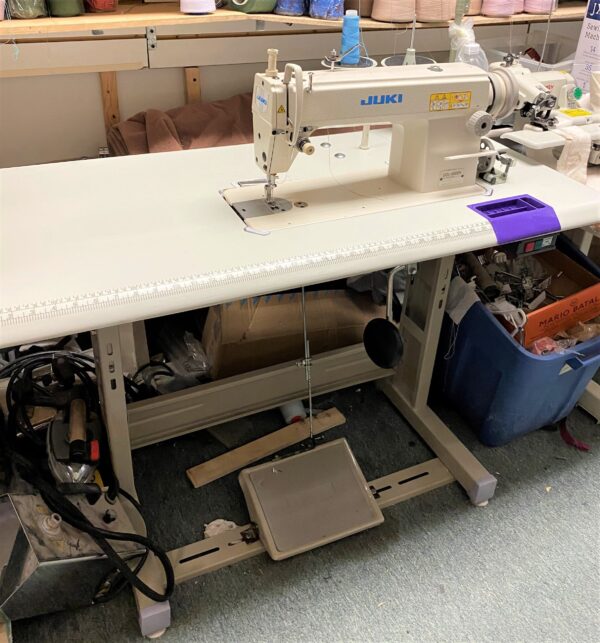 Dixie Tailoring Supply In a busy tailoring store, the JUKI DDL 5600N heavy lockstitch double-capacity hook sewing machine sits on a sturdy table, surrounded by essential crafting tools and supplies for tailor products. Tailoring Supplies