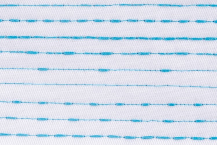Dixie Tailoring Supply White fabric sewn with evenly spaced horizontal blue lines—some dotted, some solid—created using the Jack A4E Computerized Lockstitch Machine With Electronic Stitch Length Control. Tailoring Supplies