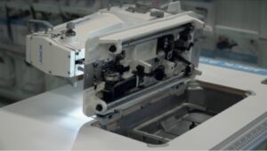 Dixie Tailoring Supply A close-up of the JACK 20U Zigzag Industrial Single Needle Sewing Machine with its front compartment open, revealing internal mechanical components. Tailoring Supplies