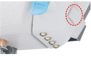 Dixie Tailoring Supply Close-up of the Jack A2 Auto Thread Cutter Industrial Sewing Machine: features a white body, three indicator lights, a blue lever, and a raised marking highlighted by a red dashed circle. Tailoring Supplies