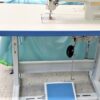 Dixie Tailoring Supply The tailoring store workshop features a JUKI DDL 8700 BRAND NEW sewing machine with a white and blue design, set on a work table. Tailoring Supplies